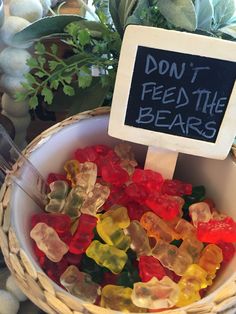 a bowl filled with gummy bears sitting on top of a table next to a sign