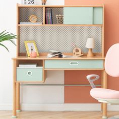 a desk with a chair and bookshelf in front of a wall painted pink