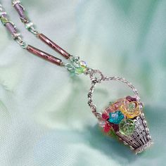 "This charming gift of flowers lasts forever. Entirely fabricated by hand, each of its elements is created from vintage tooling. Inside, a delicate arrangement of old European glass flowers and leaves features soft colors of spring -- pink, aqua, lilac, yellow and peridot. The basket pendant dangles from a chain of alternating twisted lilac glass and links with crystal accented winding leaves. Hand burnished silver finish. Made in our Los Angeles studio. Chain: 30\" Basket: 2\" x 1\"" Homemade Door Wreaths, May Flower, Basket Pendant, Mom Pendant, Aqua Earrings, Bangle Bracelet Set, Skulls And Roses, Sweet Romance, Bird Jewelry