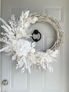 a wreath with white flowers is hanging on the front door and it's black handle