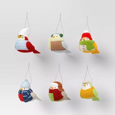 six colorful bird ornaments hanging from strings on a wall in the shape of snowmen