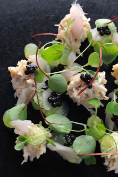 small appetizers with green leaves and blackberries on a black table top, ready to be eaten