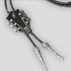 Can be worn as a hat band, too! 2•1/4” x 1•1/2” This unique bolo tie features a guitar headstock shape and a black enamel finish with silver metal accents. The tie is adjustable and suitable for both men and women, making it a versatile accessory for any occasion. The Southwestern and Western themes, combined with the punk, retro, music and dance, art, and beauty influences, make this bolo tie a great gift idea for engagement, wedding, anniversary, birthday, graduation, Valentine's Day, Father's Day, Mother's Day, or Christmas. *“FASHION & COSTUME” JEWELRY ARE THE SAME THINGS - NOT TO BE WORN EVERY DAY. THIS IS NOT “FINE” JEWELRY. 3%19F021924Y-Black/Silver Western Style Adjustable Bolo Ties For Festivals, Adjustable Silver Hat Bands For Festivals, Western Style Festival Bolo Tie, Adjustable Western Bolo Ties For Rodeo, Western Style Black Bolo Tie With Adjustable Length, Adjustable Black Bolo Tie For Rodeo, Western Black Bolo Ties For Western-themed Events, Western Black Bolo Tie With Adjustable Length, Silver Lariat Bolo Tie With Adjustable Length