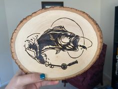 a person holding up a wooden plate with a fish on it