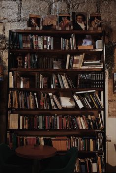 a bookshelf filled with lots of books next to a wooden table and chairs