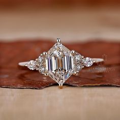 an engagement ring with three diamonds on top and a brown leaf in the foreground