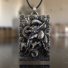 Dive into the rich tapestry of Eastern mythology with our Asian-Inspired Dragon 925 Sterling Silver Necklace. This piece embodies the spirit, power, and wisdom of the legendary Asian dragon, a symbol of prosperity, luck, and the balance of nature. Expertly crafted from premium 925 sterling silver, the necklace showcases a detailed pendant reflecting the intricate artistry of Asian dragon designs. Its unique design ensures it stands out, making it a conversation starter wherever you go. Whether y Artistic Engraved Sterling Silver Necklaces, Artistic Engraved Sterling Silver Necklace, Handmade Fantasy Silver Jewelry, Handmade Silver Fantasy Jewelry, Silver Symbolic Rectangular Jewelry, Collectible Etched Amulet Jewelry, Fantasy Style Engraved Jewelry As Gift, Fantasy Engraved Jewelry As Gift, Fantasy Style Engraved Jewelry Gift