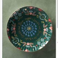 a green plate with colorful designs and writing on the bottom is sitting on a table