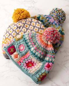 a multicolored crocheted hat with pom - pom on top