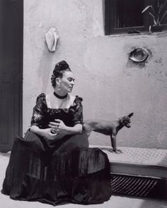 an old photo of a woman sitting on the ground next to a cat and dog