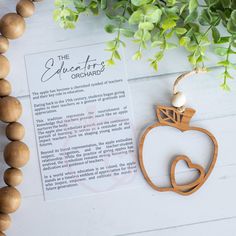 a wooden apple ornament on a table next to some wood beads and a plant