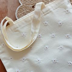 a white tote bag sitting on top of a wooden floor next to a teddy bear