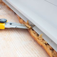 a pair of pliers cutting through the side of a piece of bread on a wooden table