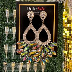 a pair of earrings hanging from the side of a display case with champagne glasses in front of it