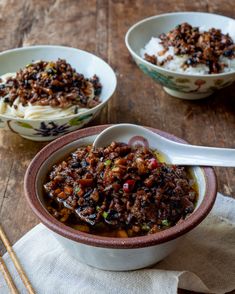 two bowls filled with food sitting on top of a wooden table next to chopsticks