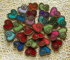 colorful hearts are arranged on a lace doily with beadwork in the middle