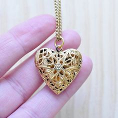 This necklace is made from a gold plated locket charm. The locket is in a shape of a simple heart and opens so you can put something special inside. The front of the locket is an intricate filigree design with cut outs. The locket hangs from a gold stainless steel chain. You can choose the style and length of the chain. Please choose the length you would like the necklace in. Please choose the chain style you would like your pendant on. Please note that all necklaces are handmade and may differ Gold Medallion Locket Necklace With Lobster Clasp, Gold-tone Pendant Locket Necklace, Gold-tone Gold Plated Pendant Locket Necklace, Gold Metal Pendant Locket Necklace, Gold-tone Gold Plated Locket Necklace Gift, Gold Locket Necklace With Adjustable Chain, Gold Round Pendant Locket Necklace With Charms, Elegant Heart Locket Charm Necklace, Gold Metal Charm Necklaces With Heart Charm