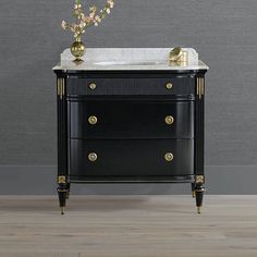 a bathroom vanity with marble top and gold accents on the bottom, in front of a gray wall