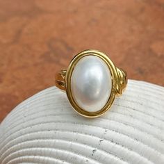 New, but old pieces, never worn, recently acquired from a premier jeweler located in Minneapolis, MN for many years- a rare opportunity! 18KT yellow Ggld genuine, bezel-set, white, oval, mabe pearl ring. Size 6.75 Sizable by us for a fee or your local jeweler Weight: 10.3 grams Band width: 3mm in back Pearl measures: 15mm x 11mm oval mabe pearl Stamped 18k By Honora Timeless Oval Rings With High Luster, Classic Gold Pearl Ring With Polished Finish, Heirloom High Luster Oval Pearl Ring, Classic Oval Ring With High Luster, Classic Oval Rings With High Luster, Yellow Gold Oval Pearl Ring With Polished Finish, Oval Yellow Gold Pearl Ring With High Luster, Oval Pearl Ring In Yellow Gold With High Luster, Classic Oval High Luster Ring