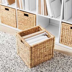 wicker baskets are stacked on the floor in front of bookshelves