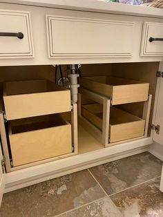 an open cabinet door with drawers on the bottom and bottom, in front of a tile floor