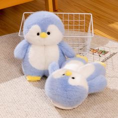 two blue and white stuffed animals sitting next to each other on a rug in front of a basket