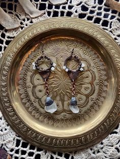 a gold plate with two pairs of dangling earrings on it sitting on a lace doily