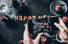 someone holding up their phone to take a photo with the happy new year message on it