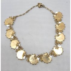 This is part of Chairish’s Costume Jewelry assortment.  Mid to late 1950s goldtone white thermoset molded daisies collar necklace with hook clasp. Marked crown "TRIFARI©" on the clasp. Measures: 5 1/2 inches long by 6 1/2 inches wide. Interior circumference is about 15 1/2 inches at the largest setting. Condition: The front section is in good condition, but there is some wear/fading primarily to the chain, clasp and back. 1950s Jewelry Necklaces, White Multi-strand Costume Jewelry Necklace, Gold Flower-shaped Costume Jewelry Necklace, 1950s Pearl Necklace, Gold Costume Jewelry Necklace, 16 Inch Length, Crown Trifari, Daisy Necklace, Hook Clasp, Accessories Jewelry Necklace