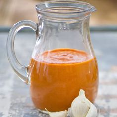 a glass pitcher filled with liquid next to garlic