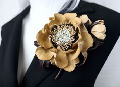 a man wearing a suit and tie with a flower brooch on his lapel