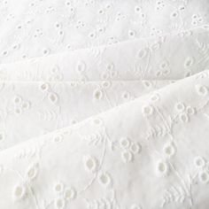 closeup of white embroidered fabric with flowers on it