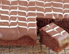 chocolate cake with white frosting on a cooling rack and one slice cut out from it