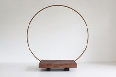 a wooden stand with a metal ring on it's end and a white wall in the background