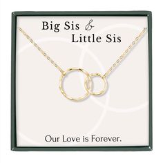 a necklace with two interlocked circles on it and the words, big sis & little siss our love is forever