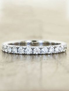 a wedding band with round cut diamonds on the bottom and sides, sitting on a table