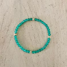 a green beaded bracelet sitting on top of a wooden table