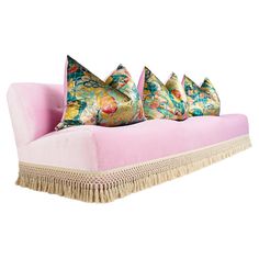 three pink couches with colorful pillows on them and fringe trimming around the edges