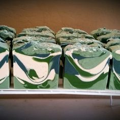 soaps are stacked up on a shelf in a display case with green and white swirled designs