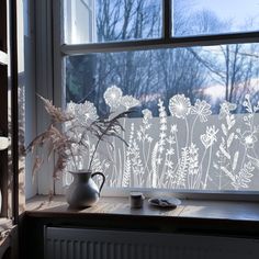 a vase with some flowers sitting on a window sill next to a glass wall