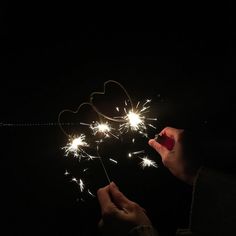 someone holding a sparkler in the dark with their hand and heart shape on it