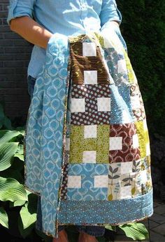 a woman wearing a blue shirt holding a patchwork bag