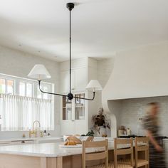 a blurry image of a kitchen with an island in the middle and chairs around it