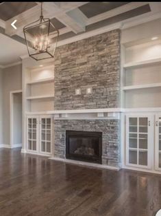 an empty living room with stone fireplace and built - in bookcases