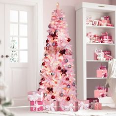 a pink christmas tree with presents under it in a room decorated for the holiday season