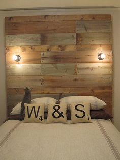 a bed with two pillows on it in front of a headboard made out of wood planks