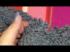 someone is crocheting the edge of a blanket with their finger and thumbnails