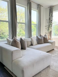 a white couch sitting in front of two large windows