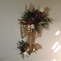 a gold skeleton with flowers and greenery hanging on the wall