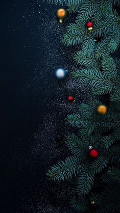 a christmas tree with ornaments on it in the dark night, surrounded by stars and snow flakes